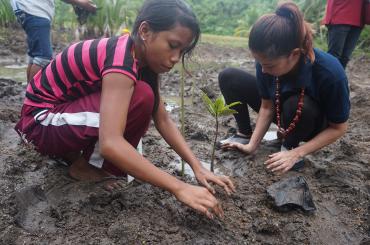 Rainalyn of Decabobo helping out Ms. Antoinette Taus, UNDP Ambassador, to plant a mangrove seedling.